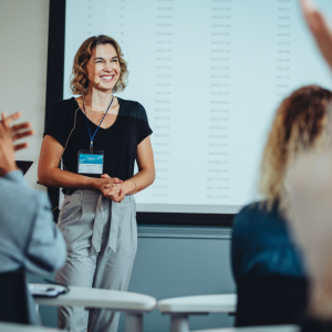 Blonde professional woman presenting and smiling to a group of people